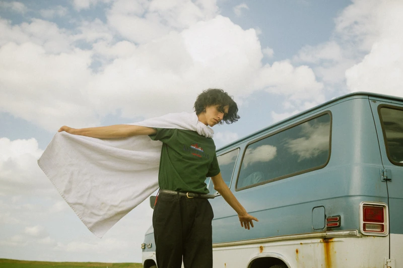 A portrait beside a van with fabric moving in the open air